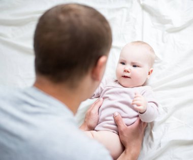 Mutlu genç baba evde küçük bir kızla oynuyor.