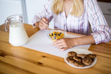 Sağlıklı kahvaltı kavramı - pijamalı kadın modern mutfakta yemek yiyor