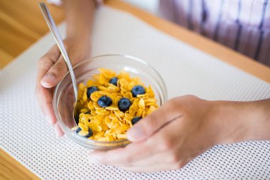 Sağlıklı kahvaltı kavramı - cam kasede yaban mersinli mısır gevreğine yakın çekim