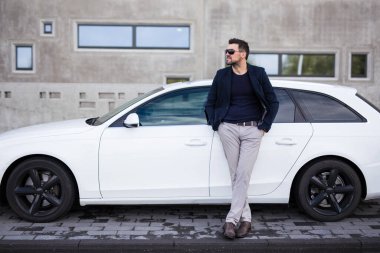 Modern beyaz arabasıyla yakışıklı bir adamın portresi.