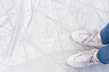 Paten kayan kadın bacaklarının üst görüntüsü ve buz pistindeki beyaz çizik alanının üzerindeki boşluğu kopyala