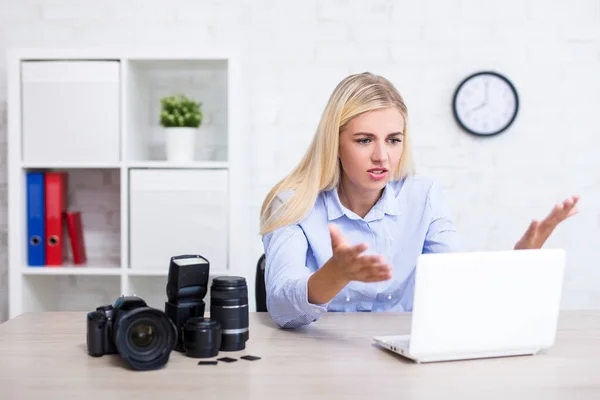 sad or angry female photographer with camera and photography equipment having problems with computer
