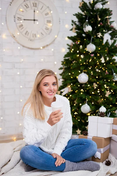 幸せな若い女性の肖像画装飾されたクリスマスツリーとリビングルームでコーヒーを飲む — ストック写真