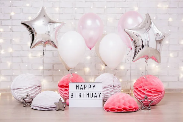 Doğum günü partisi konsepti - hava balonlarının, kağıt topların ve ışık kutusunun kapanışı Mutlu yıllar yazılı tuğla duvarın üzerinde ışıklarla