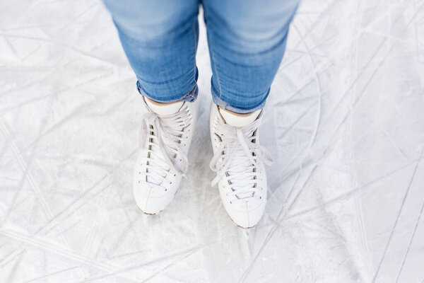 верхний вид ног в новых коньках над белым льдом на катке
