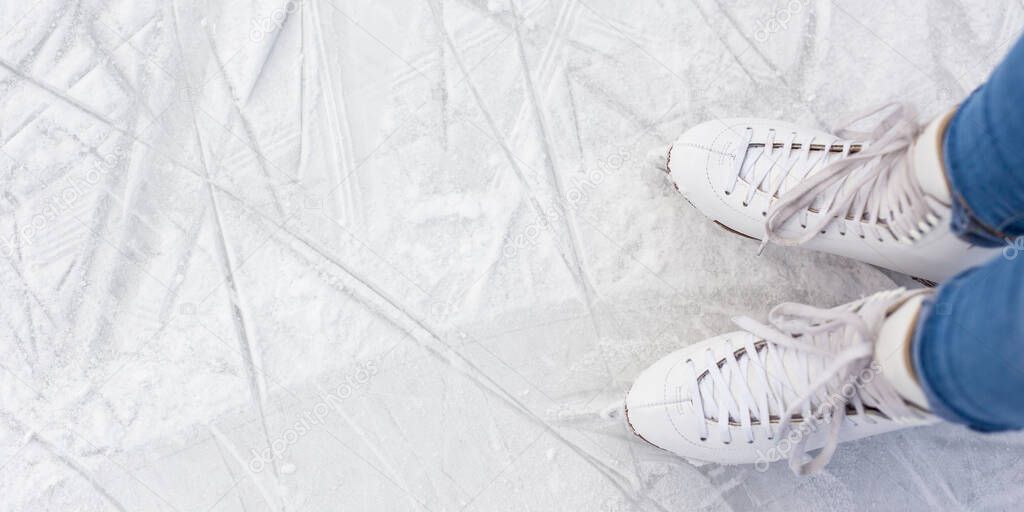 top view of female legs in skates and copy space over white ice at rink