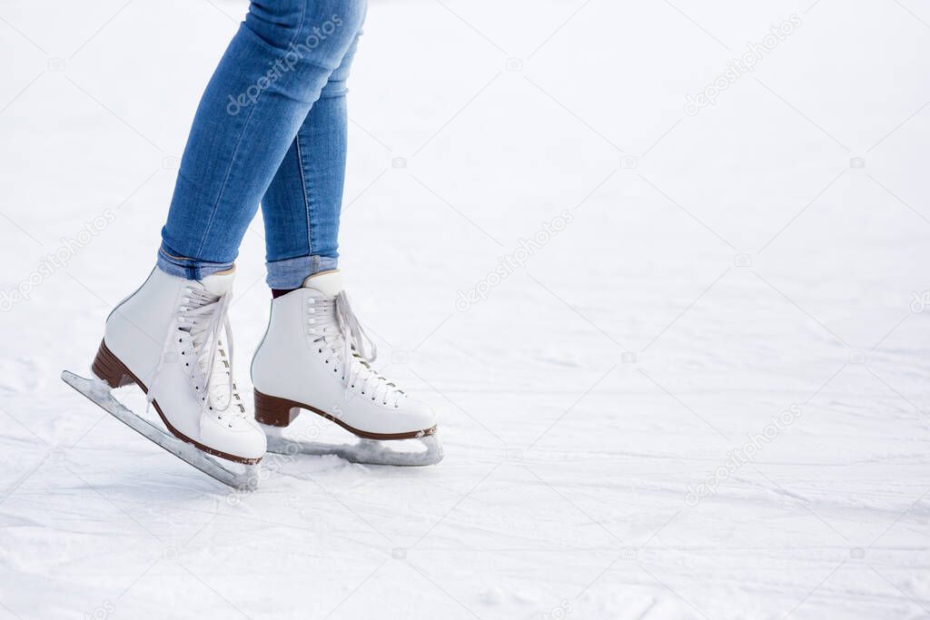 legs in white leather skates and copy space over white ice at rink