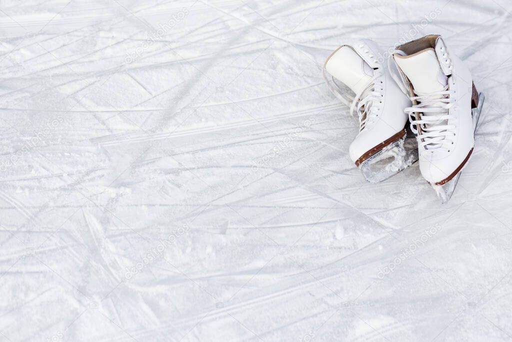 close up of white figure skates and copy space over ice background with marks from skating