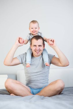 Genç adam baba ve küçük tatlı kız omuzlarında oturup evde birlikte eğleniyorlar.