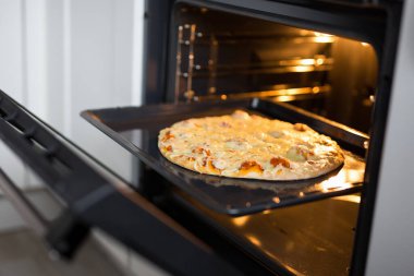 Sıcak fırında ev yapımı peynirli pizzaya yakın durun.