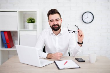 Modern ofiste bilgisayar kullanan neşeli sakallı iş adamının portresi.