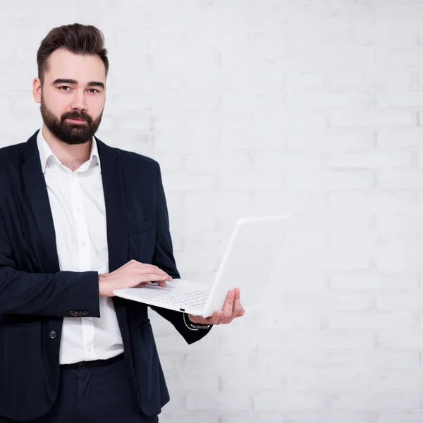 Porträt Eines Jungen Bärtigen Geschäftsmannes Der Computer Über Weißem Backsteinhintergrund — Stockfoto