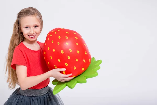 可愛い女の子のポートレートとともに大きな人工イチゴとコピースペース上の白い背景 — ストック写真