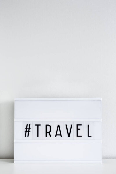 Retro light box with travel hash tag and copy space over white wall background