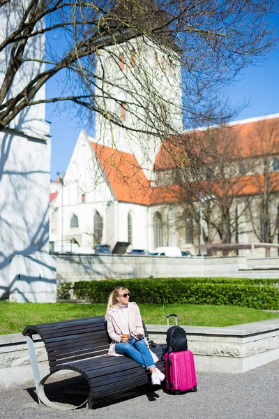 夏の旅行と休暇のコンセプト エストニアのタリンの旧市街にあるコーヒーとスーツケースを着た若い女性 — ストック写真