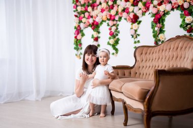 Anneler Günü konsepti. Mutlu güzel anne ve küçük kızı çiçek duvarının arkasında poz veriyorlar.