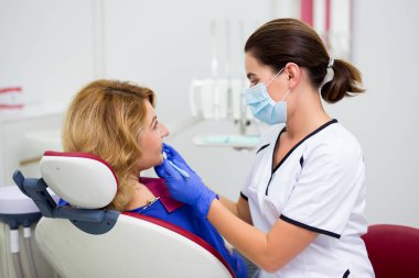 Genç bayan dişçi dişçi, dişçi kliniğinde dişlerini muayene ediyor.