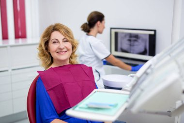 Diş kliniğinde oturan olgun kadın portresi.