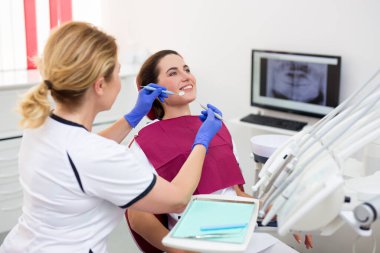 Modern diş kliniğinde mutlu kadın hastalarla çalışan dişçi.
