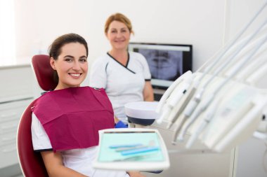 Modern diş kliniğinde gülümseyen genç bir kadın.