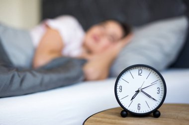 Sabah konsepti - genç uyuyan kadın ve çalar saat evde yatak odasında