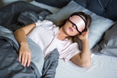 İyi geceler ya da sabah konsepti. Gece maskeli güzel bir kadın yatağında uyuyor.