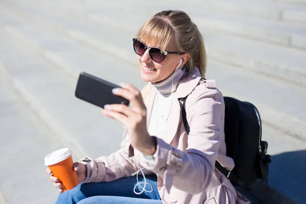 ライフスタイルと旅行のコンセプト 階段に座ってスマートフォンで写真を撮る若い美しい女性 — ストック写真