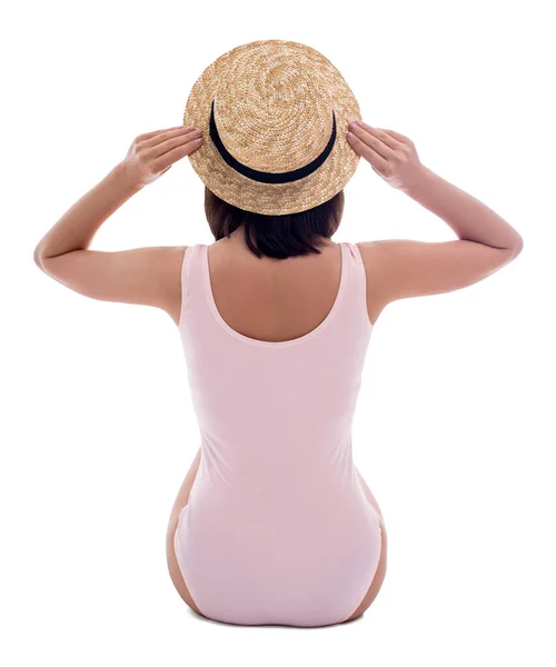 穿着粉色泳衣 戴着草帽 孤零零地坐在白色背景上的年轻女子的背影 — 图库照片