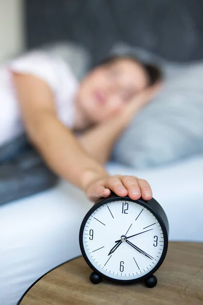 早睡早起的概念 年轻困倦的女人在卧室里带着闹钟醒来 — 图库照片