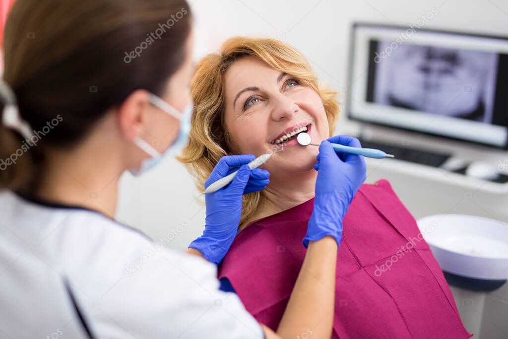 dentist with happy female patient at modern clinic