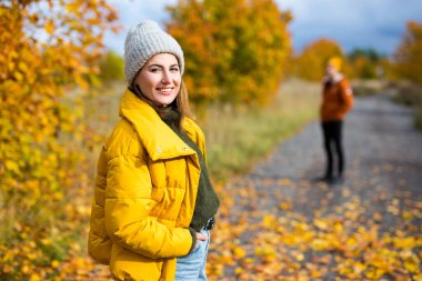 Sonbahar parkında erkek arkadaşıyla yürüyen mutlu genç bir kadının portresi.