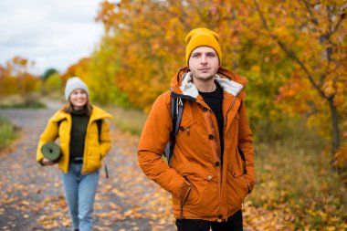 Sonbahar parkında ya da kız arkadaşıyla ormanda poz veren yakışıklı bir adamın portresi.