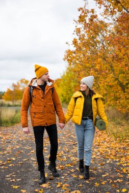 Sırt çantalı şirin bir çift sonbahar ormanında yürüyor.