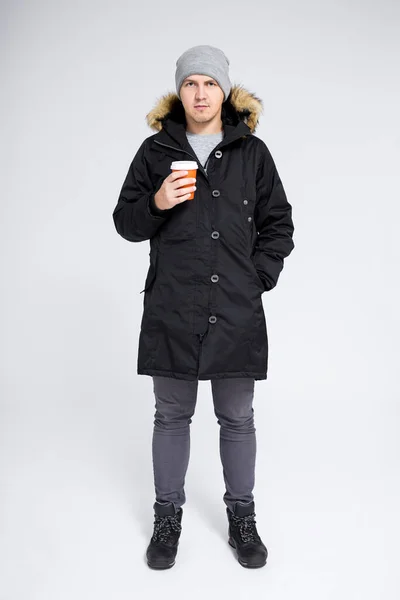 秋の長さの肖像画の若いですハンサムな男で暖かい冬のジャケット飲料コーヒーや紅茶以上グレーの背景 — ストック写真