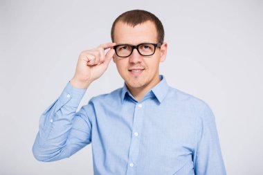 Gözlüklü bir iş adamının portresi gri arka planda kameraya bakıyor.