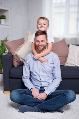 Mutlu baba ve küçük oğlunun portresi modern oturma odasında oturuyor.