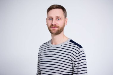 Beyaz arka planda poz veren yakışıklı sakallı adamın portresi.