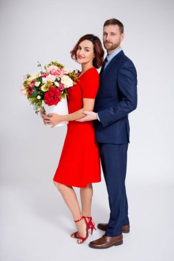 Sevgililer Günü ya da doğum günü sürpriz konsepti. Yakışıklı bir adam beyaz arka planda çiçeklerle sevgilisini şaşırtıyor.