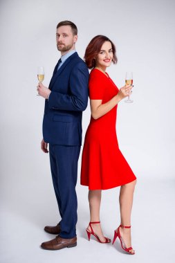 Sevgililer günü, Noel ve yeni yıl konsepti. Beyaz arka planda şampanya kadehleriyle poz veren zarif genç bir çiftin tam boy portresi.