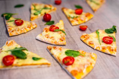 Domatesli ve otlu lezzetli pizza dilimlerini ahşap masa arkasında kapatın.