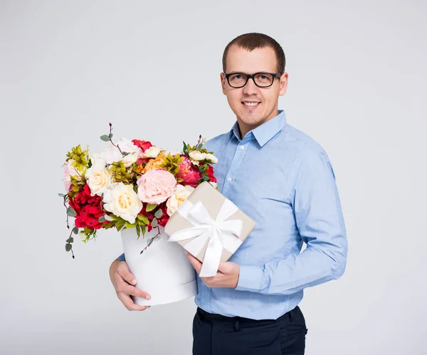 情人节或母亲节的概念 年轻英俊男子的肖像 灰色背景下的花朵和礼品盒 — 图库照片