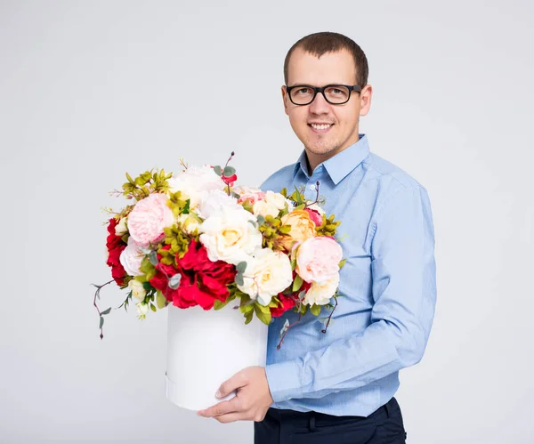 バレンタインデーや母の日のコンセプト 花の箱を持つ若いハンサムな男の肖像画 — ストック写真
