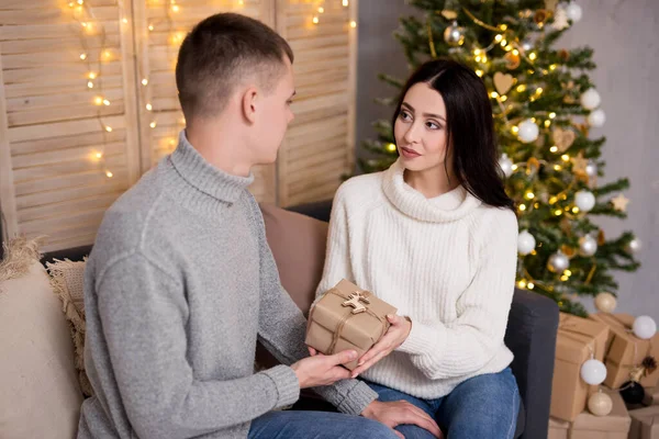 クリスマスと愛のコンセプト ハンサムな男を与えるクリスマスプレゼントに彼のガールフレンド — ストック写真