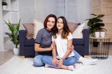 Oturma odasında oturan mutlu anne ve kızın portresi.