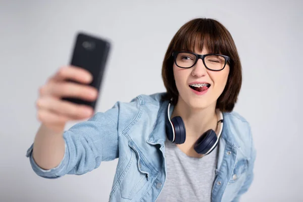 Gri Arka Planda Akıllı Telefonla Fotoğraf Çeken Komik Genç Kadın — Stok fotoğraf