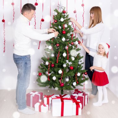 Genç mutlu anne-baba ve kız evde Noel ağacı süslüyorlar.