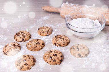 Kış arkaplanı - ahşap masada un ile taze pişmiş çikolatalı kurabiyeler