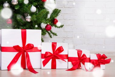 Süslü Noel ağacının altında renkli toplarla uçan kar taneleri olan hediye kutularını kapatın.