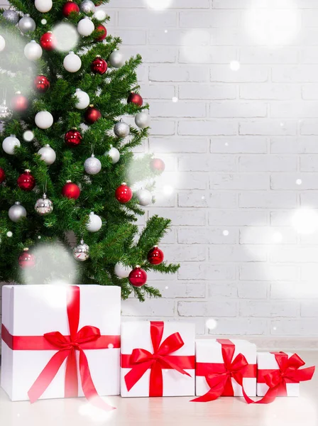 Kerstachtergrond Geschenkdozen Onder Versierde Kerstboom Bakstenen Muur Vliegende Sneeuwvlokken — Stockfoto