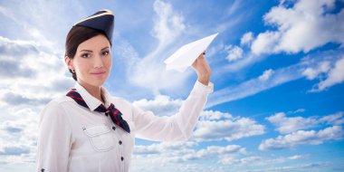 Mavi arka planda kağıt uçakla uçan genç hostes.